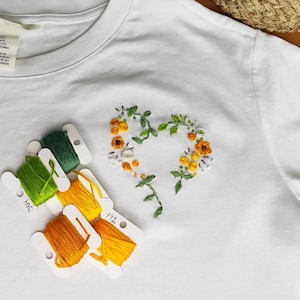 Hand embroidery on a T-shirt. Beautiful and delicate embroidered heart. T-shirt design. Decorating clothes with embroidery